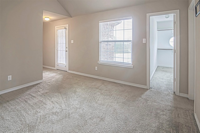 spare room featuring vaulted ceiling and light colored carpet