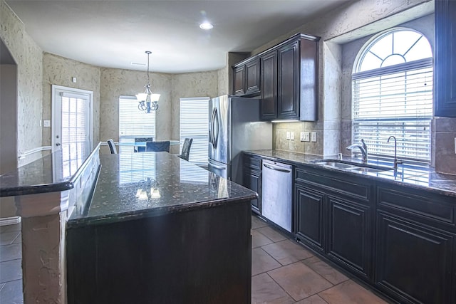 kitchen with sink, decorative light fixtures, stainless steel appliances, and a center island