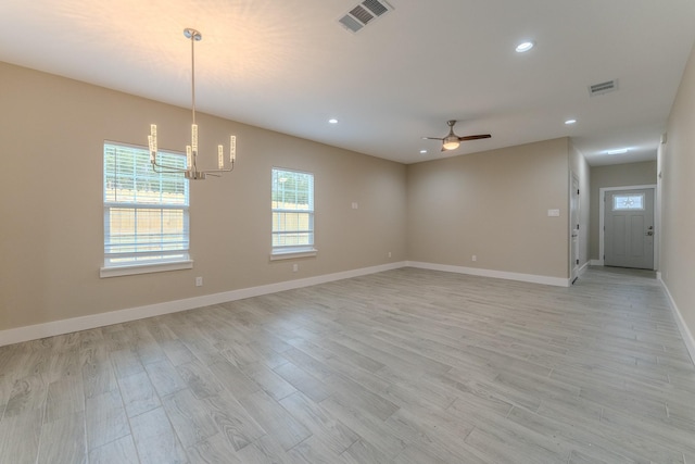 unfurnished room featuring ceiling fan with notable chandelier and light hardwood / wood-style floors