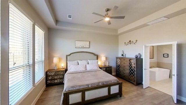 bedroom with a tray ceiling, wood-type flooring, and ceiling fan