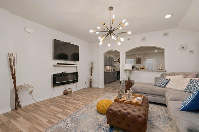 living room with lofted ceiling, a chandelier, and light hardwood / wood-style floors