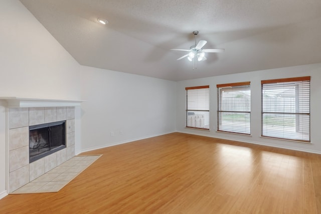 unfurnished living room with ceiling fan, a fireplace, a textured ceiling, and light wood-type flooring