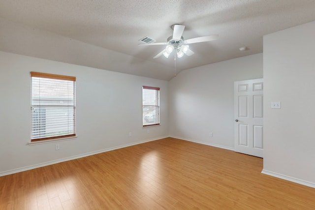 spare room featuring lofted ceiling, a textured ceiling, ceiling fan, and light wood-type flooring