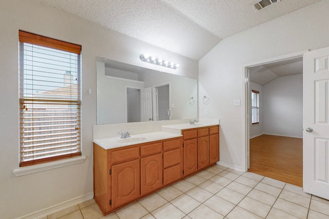 bathroom with lofted ceiling, tile patterned flooring, vanity, and a textured ceiling