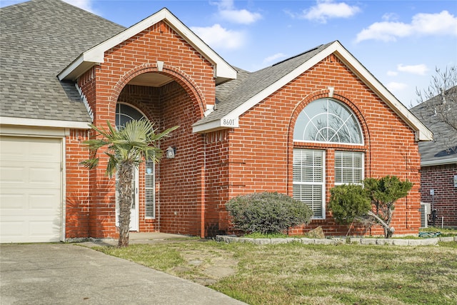 view of front of home featuring central AC, a garage, and a front lawn