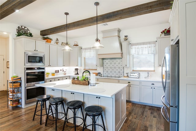 kitchen with a center island, custom range hood, pendant lighting, stainless steel appliances, and white cabinets