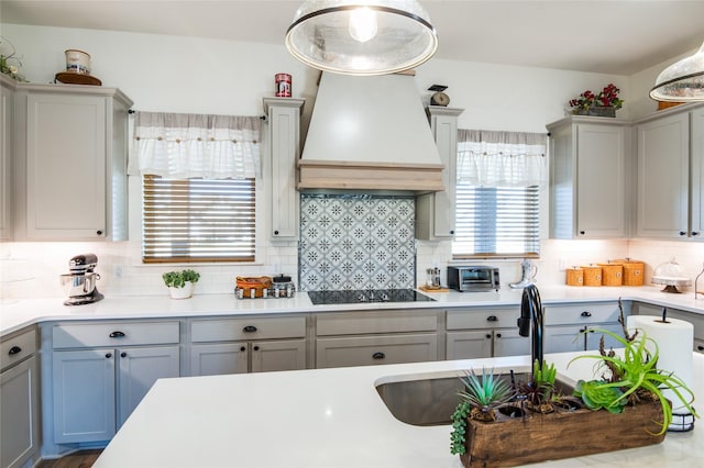 kitchen featuring sink, gray cabinetry, backsplash, custom exhaust hood, and black electric stovetop