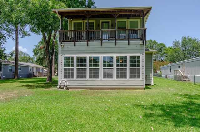 back of property featuring a balcony and a yard