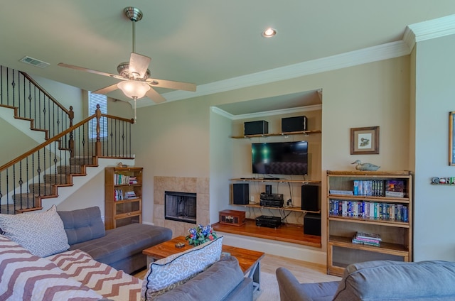 living room with crown molding, light hardwood / wood-style floors, a tile fireplace, and ceiling fan