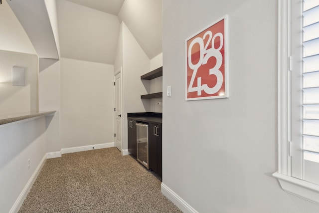 interior space featuring carpet, beverage cooler, and lofted ceiling