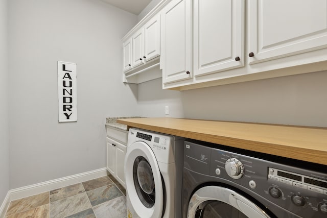 laundry room featuring stone finish floor, cabinet space, baseboards, and independent washer and dryer