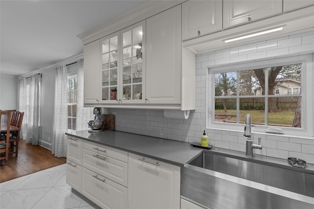 kitchen with white cabinetry, ornamental molding, sink, and backsplash