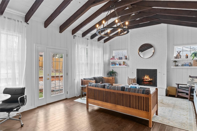 living room featuring an inviting chandelier, a fireplace, wood-type flooring, and lofted ceiling with beams