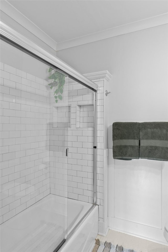 bathroom featuring ornamental molding and combined bath / shower with glass door