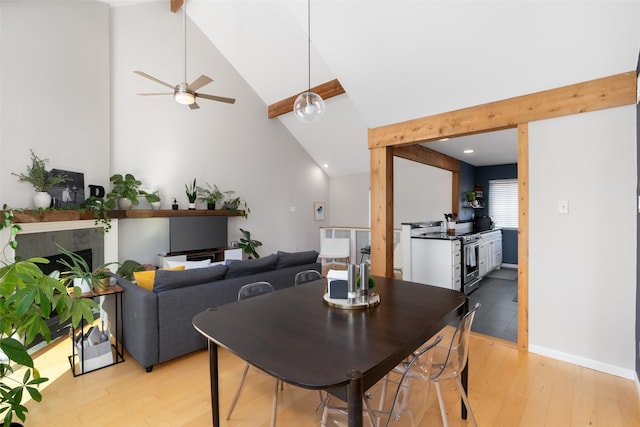 dining area with ceiling fan, beam ceiling, high vaulted ceiling, and light wood-type flooring