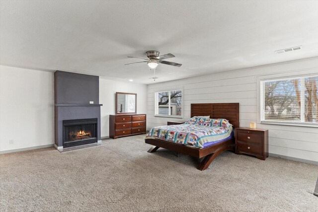 bedroom featuring light carpet, a textured ceiling, a fireplace, and ceiling fan