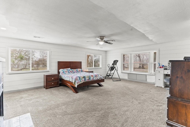 carpeted bedroom with multiple windows, ceiling fan, and a textured ceiling