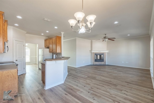 kitchen with a fireplace, decorative light fixtures, white fridge, light hardwood / wood-style floors, and kitchen peninsula