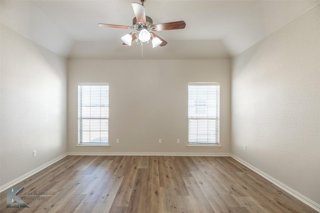 empty room with ceiling fan, a wealth of natural light, and light wood-type flooring