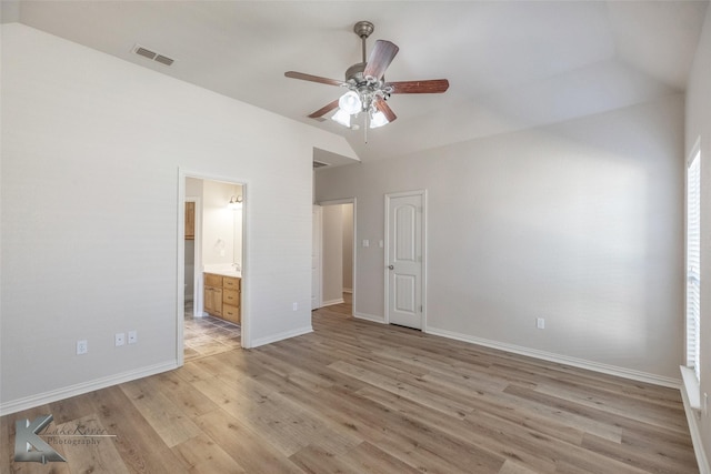 unfurnished bedroom featuring ceiling fan, lofted ceiling, connected bathroom, and light wood-type flooring