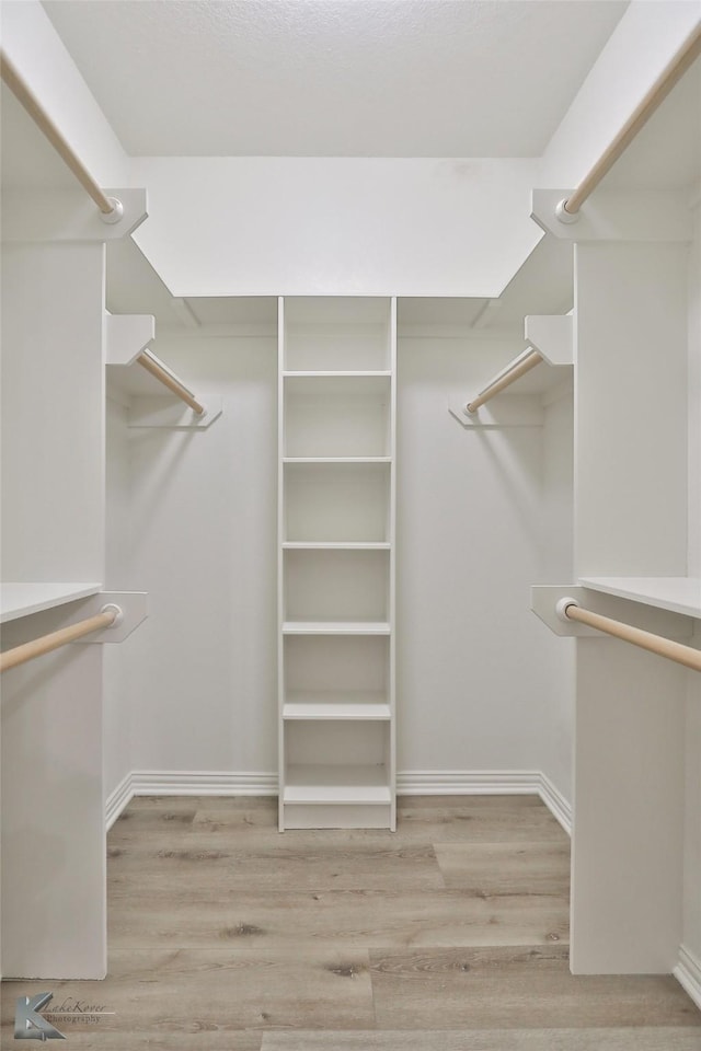 walk in closet with light hardwood / wood-style flooring