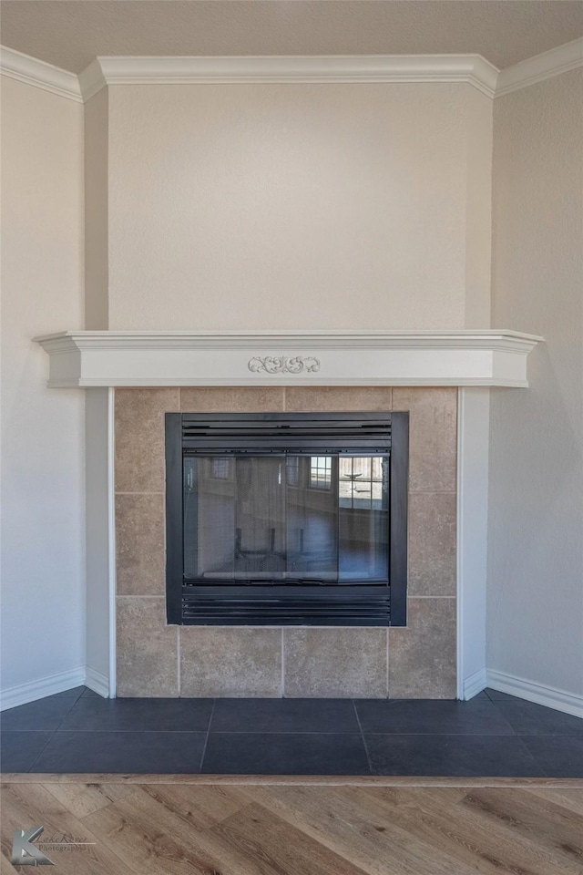 room details with a tiled fireplace, ornamental molding, and wood-type flooring