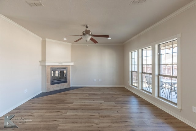 unfurnished living room featuring a tiled fireplace, dark wood-type flooring, ornamental molding, and ceiling fan