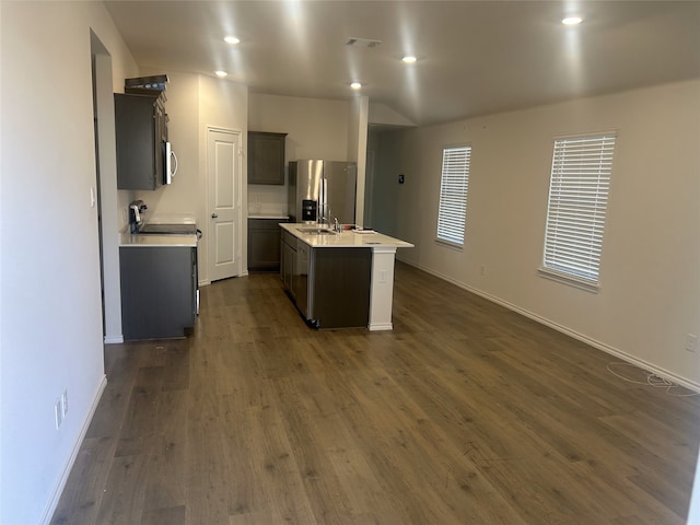 kitchen with sink, appliances with stainless steel finishes, dark hardwood / wood-style floors, and an island with sink