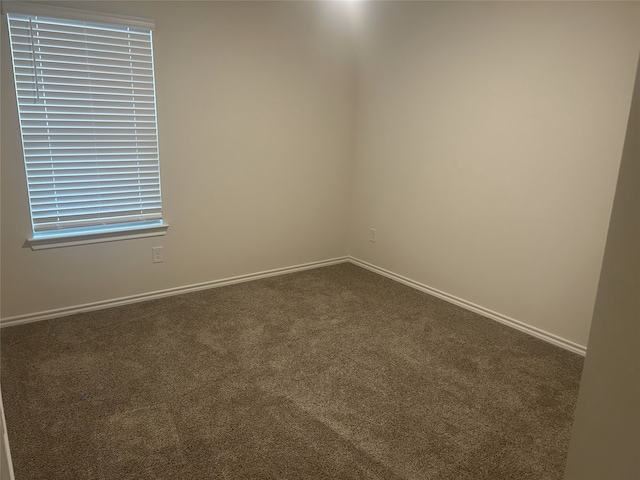 spare room with dark colored carpet