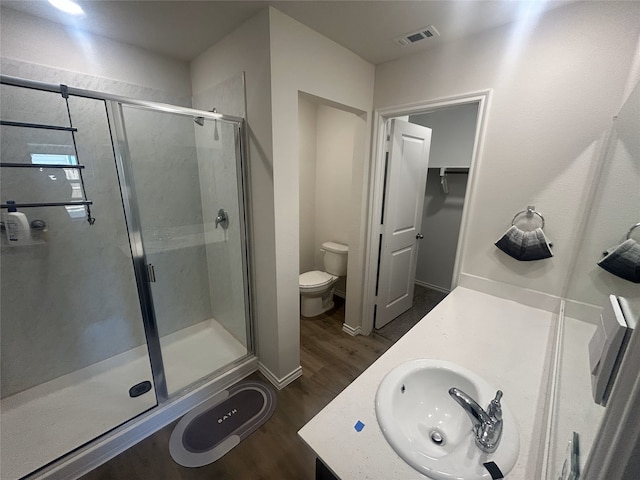 bathroom featuring vanity, hardwood / wood-style floors, an enclosed shower, and toilet