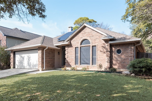 view of front of property with a garage, a front yard, and solar panels