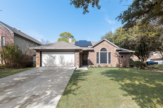 view of front of property with a garage, a front yard, and solar panels