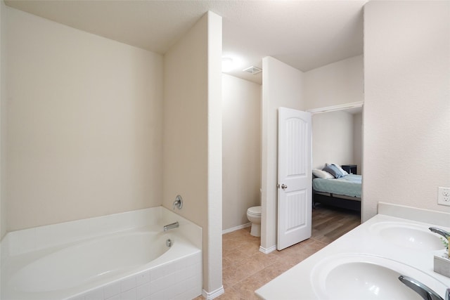 bathroom featuring toilet, vanity, tiled bath, and tile patterned flooring