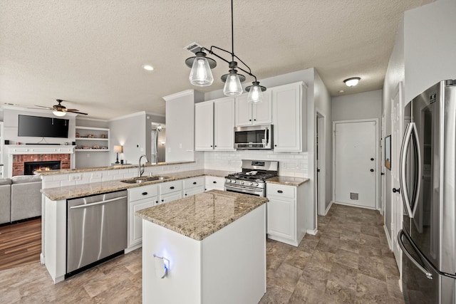 kitchen with sink, white cabinets, hanging light fixtures, a center island, and stainless steel appliances