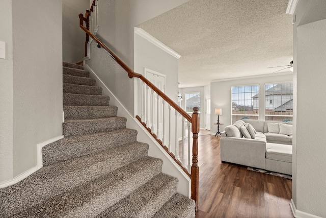 stairs featuring ceiling fan, ornamental molding, wood-type flooring, and a textured ceiling