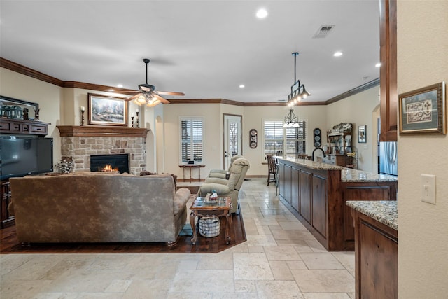 living room with crown molding, ceiling fan, and a fireplace