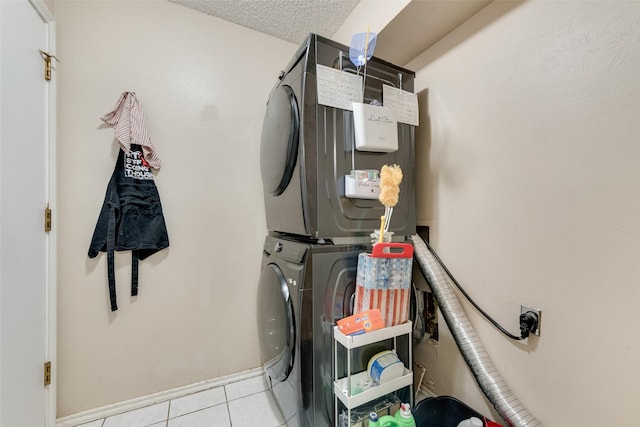 clothes washing area featuring light tile patterned floors, a textured ceiling, and stacked washing maching and dryer