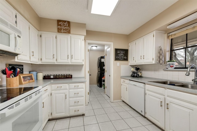 kitchen featuring sink, white appliances, light tile patterned floors, white cabinetry, and decorative backsplash