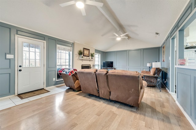 living room featuring lofted ceiling with beams, ceiling fan, light hardwood / wood-style floors, and a textured ceiling