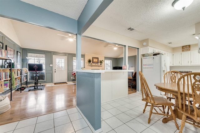 kitchen featuring white refrigerator with ice dispenser, white cabinets, ceiling fan, and kitchen peninsula