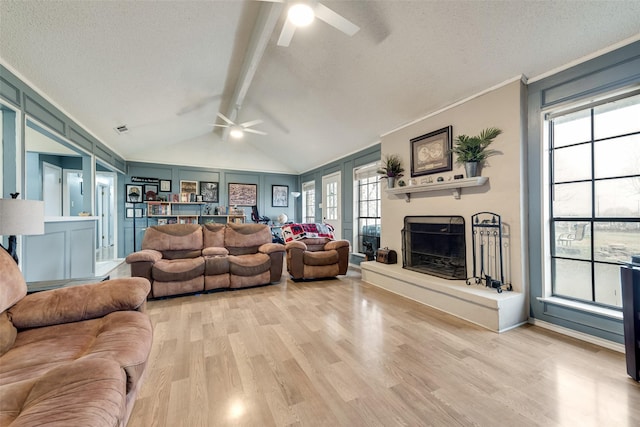 living room with vaulted ceiling with beams, a textured ceiling, and light wood-type flooring