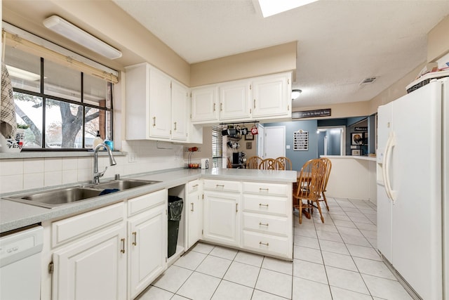 kitchen featuring sink, white appliances, light tile patterned floors, white cabinetry, and kitchen peninsula