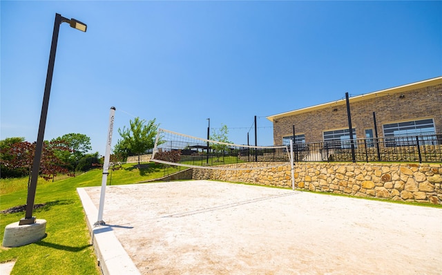 view of property's community with a lawn and volleyball court