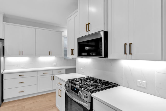 kitchen with white cabinetry, light wood-type flooring, stainless steel appliances, and decorative backsplash