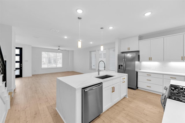 kitchen featuring white cabinetry, an island with sink, stainless steel appliances, sink, and pendant lighting