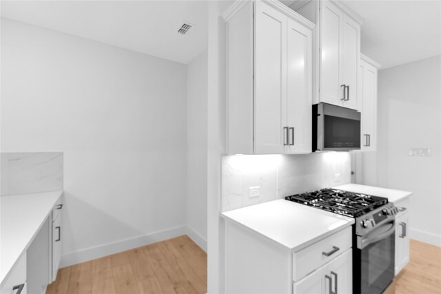 kitchen featuring light wood-type flooring, appliances with stainless steel finishes, and white cabinetry