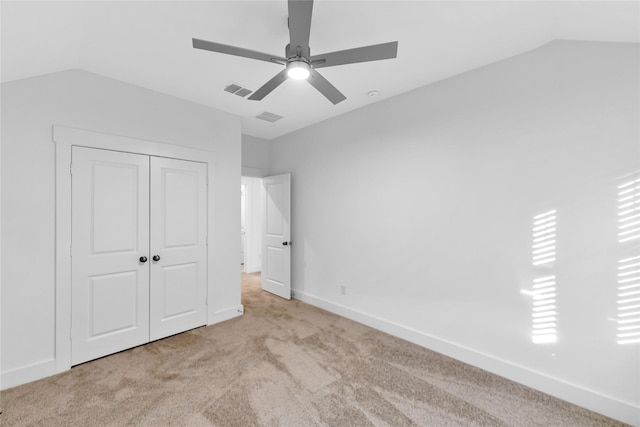 unfurnished bedroom featuring light carpet, lofted ceiling, ceiling fan, and a closet