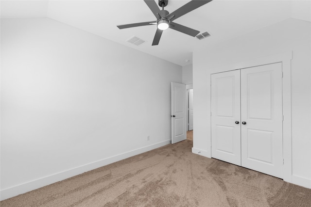 unfurnished bedroom featuring a closet, lofted ceiling, light colored carpet, and ceiling fan