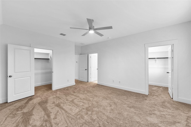 unfurnished bedroom featuring ceiling fan, light carpet, a closet, and a spacious closet