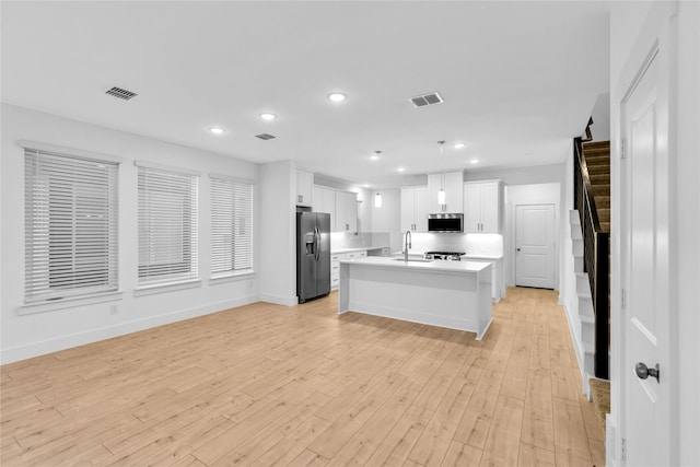 kitchen with white cabinetry, a center island with sink, stainless steel appliances, and pendant lighting